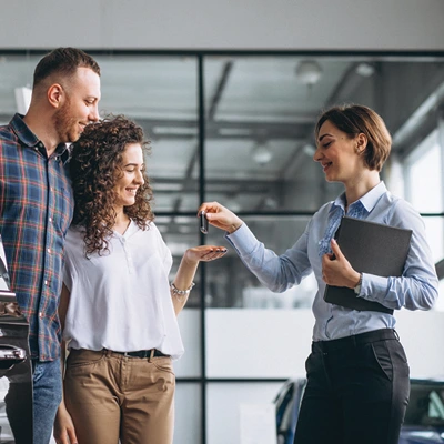 Couple receiving car keys from a sales woman